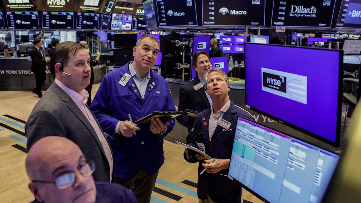 Traders on the floor of the New York Stock Exchange review market data as earnings season and Federal Reserve minutes dominate the week ahead