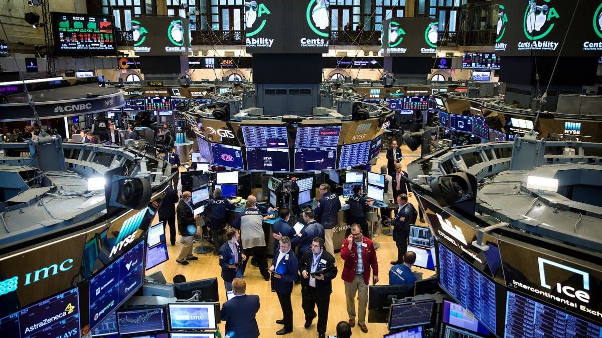 NYSE trading floor with traders and market data screens showing active session
