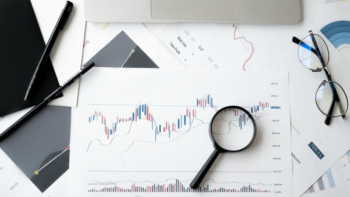 Magnifying glass over stock market candlestick charts and financial graphs