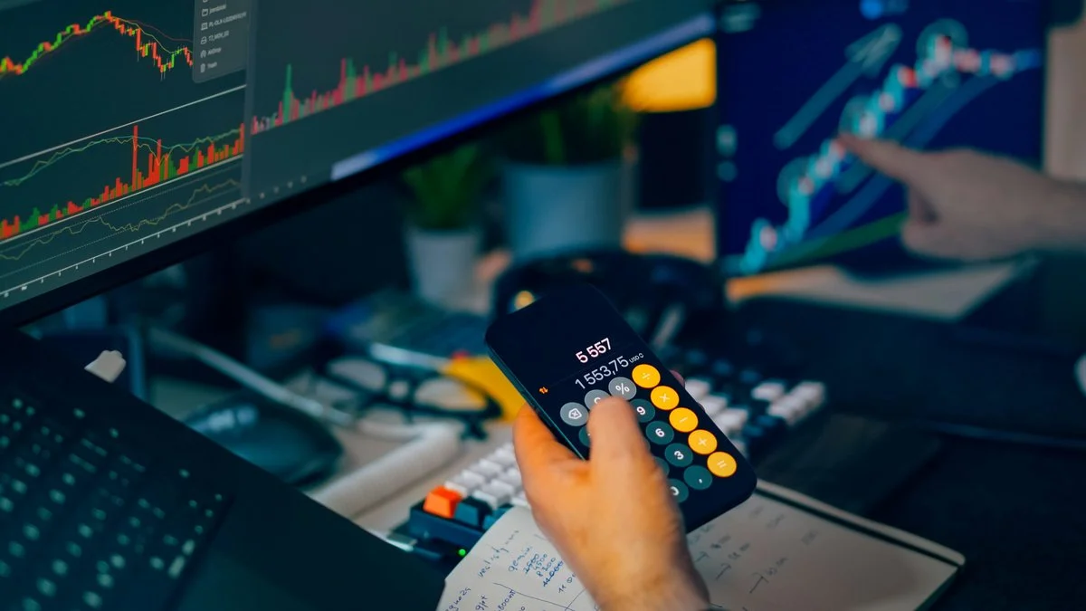 Financial analyst reviewing stock market charts and economic data on multiple screens