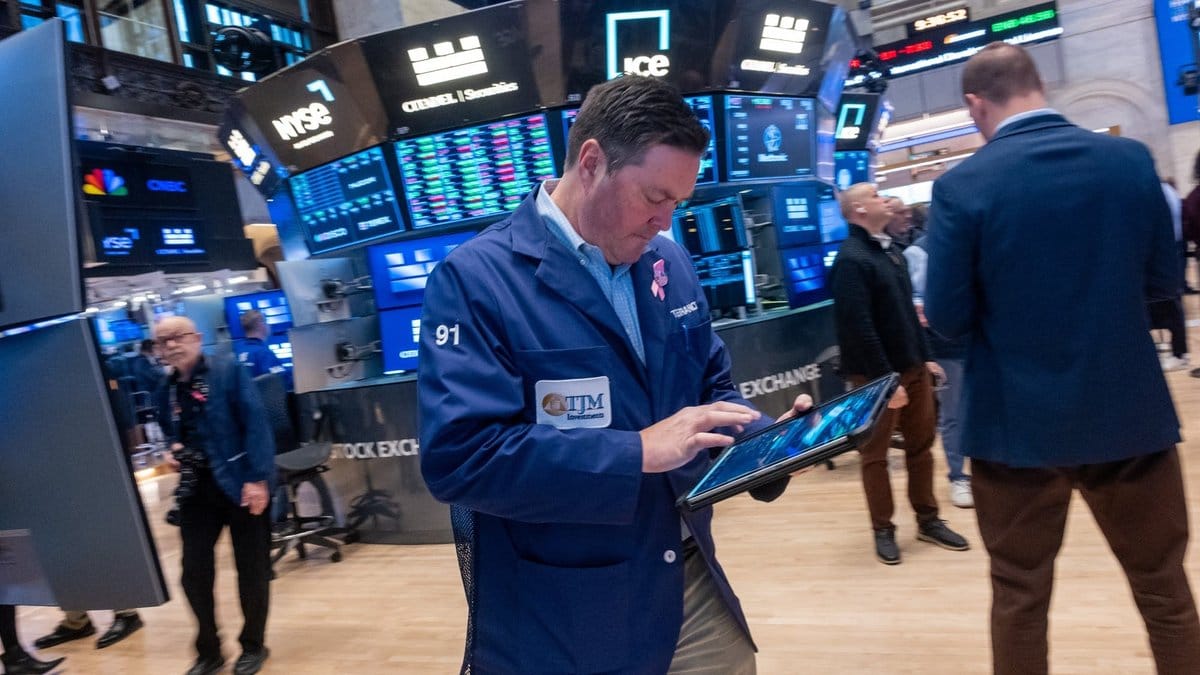 NYSE trading floor during earnings season with traders monitoring market data