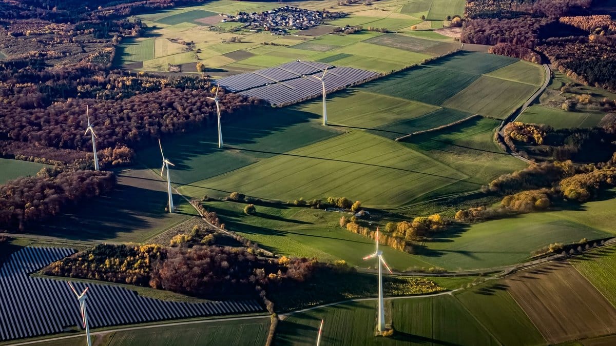 Aerial view of wind turbines and solar panels in a rural European landscape — renewable energy transition