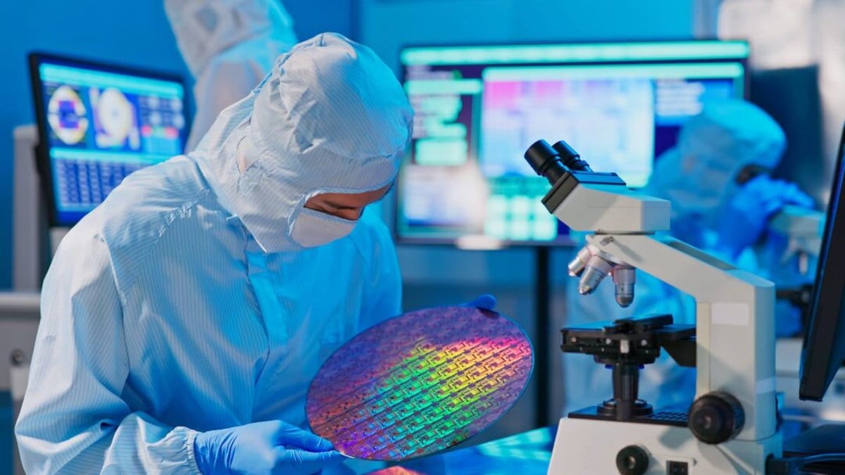 Semiconductor engineer inspecting a silicon wafer in a cleanroom facility