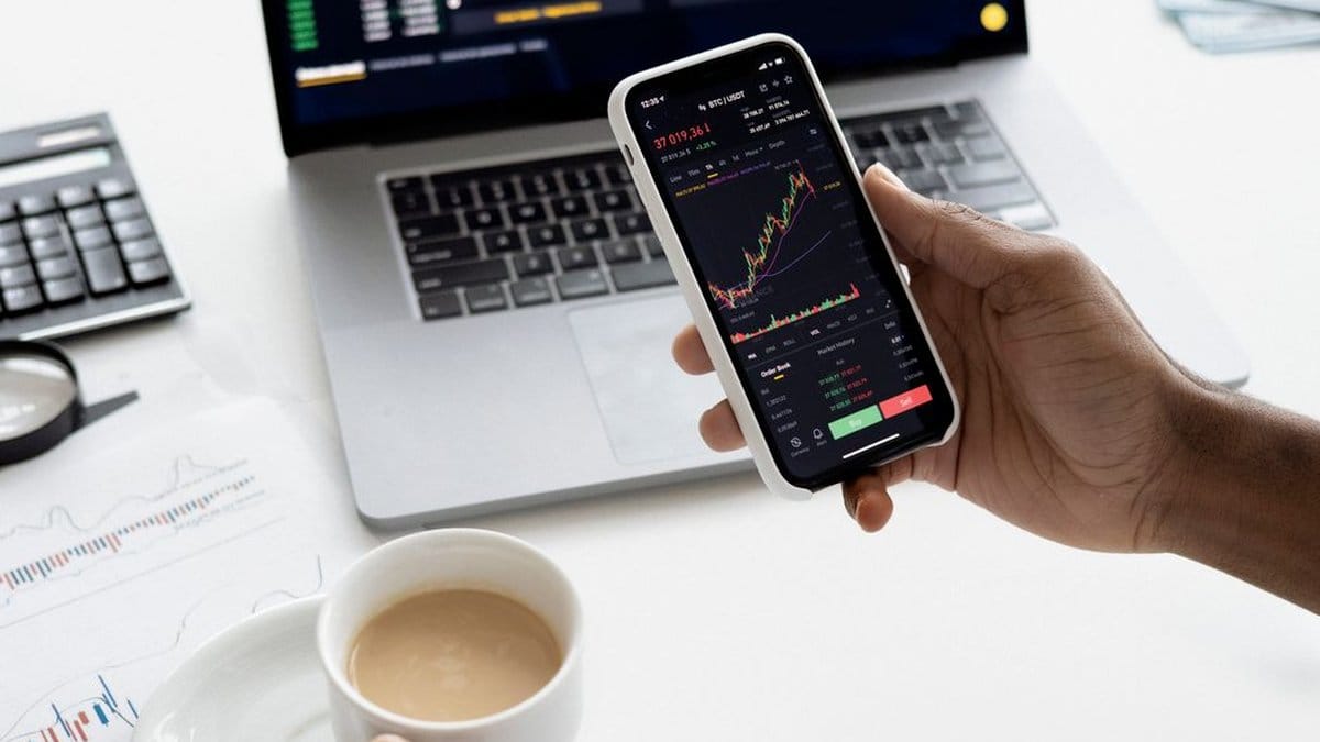 Investor reviewing market data on smartphone and laptop