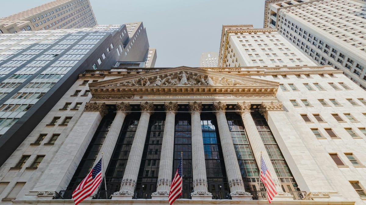 New York Stock Exchange building exterior on Wall Street with American flags