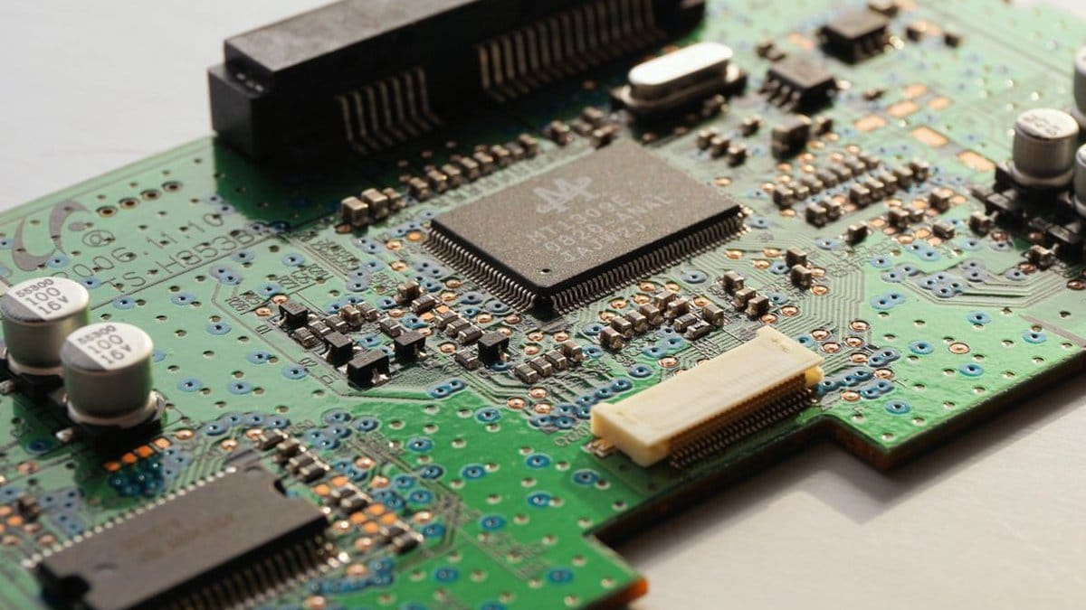 Close-up of a green printed circuit board with a microchip, representing semiconductor technology