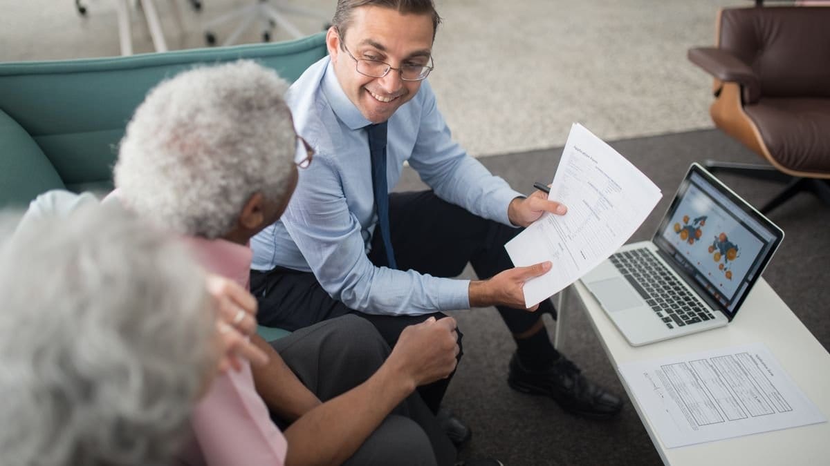 Financial advisor reviewing retirement planning documents with senior client in professional office setting