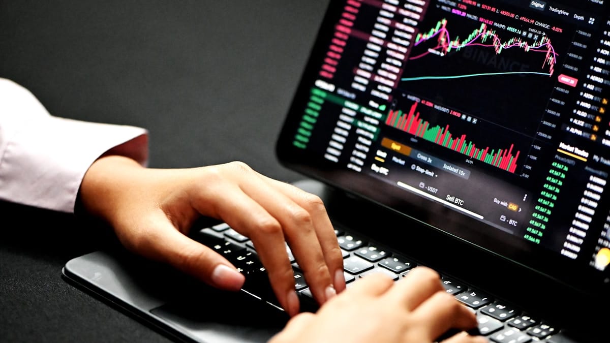 Financial professional analyzing cryptocurrency trading charts on a laptop