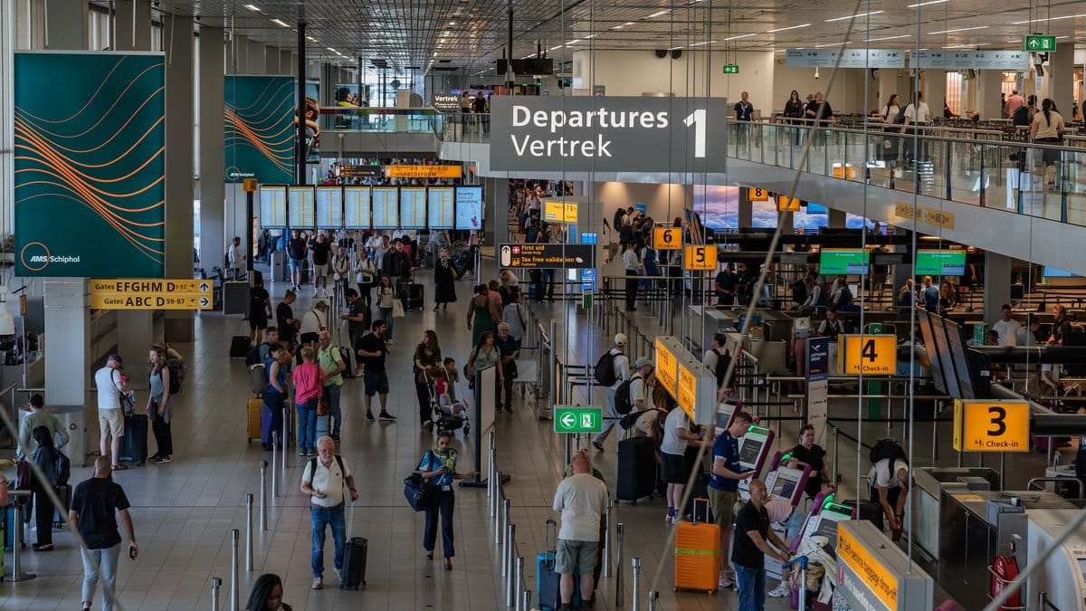 Travelers moving through a busy airport departure hall during the summer travel season