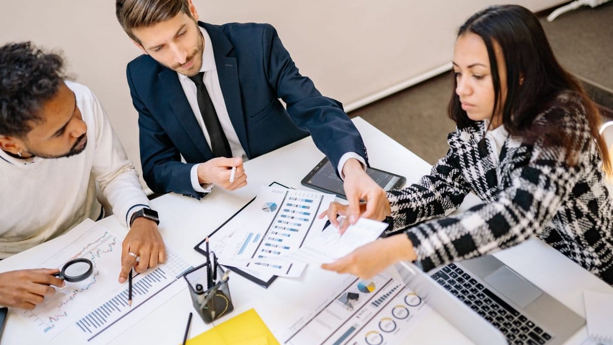 Diverse financial professionals reviewing economic charts and market data in an office