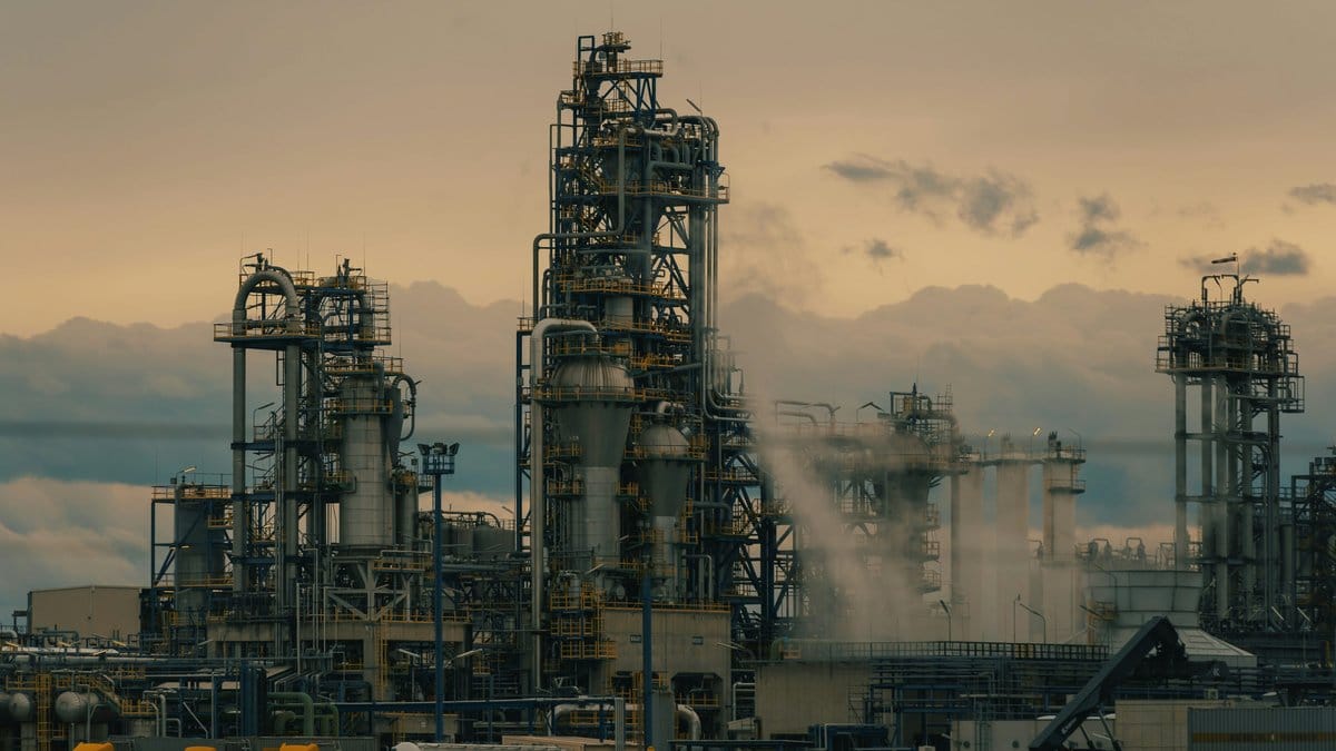 Oil refinery at dusk representing surging crude oil prices and energy market volatility