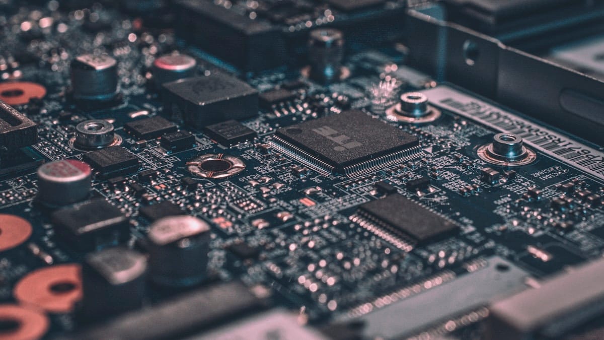 A macro photograph of a dark blue circuit board with various semiconductor components