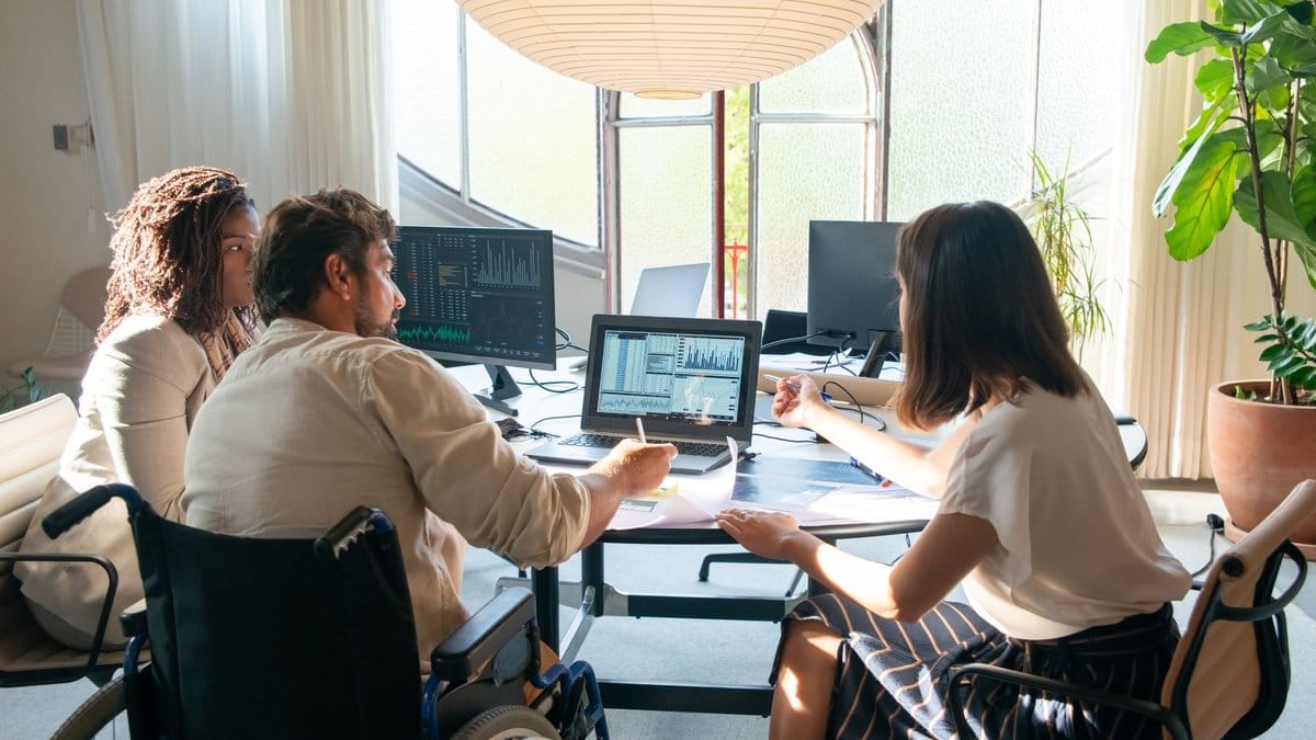 Diverse market-analysis team reviewing financial screens in a bright office