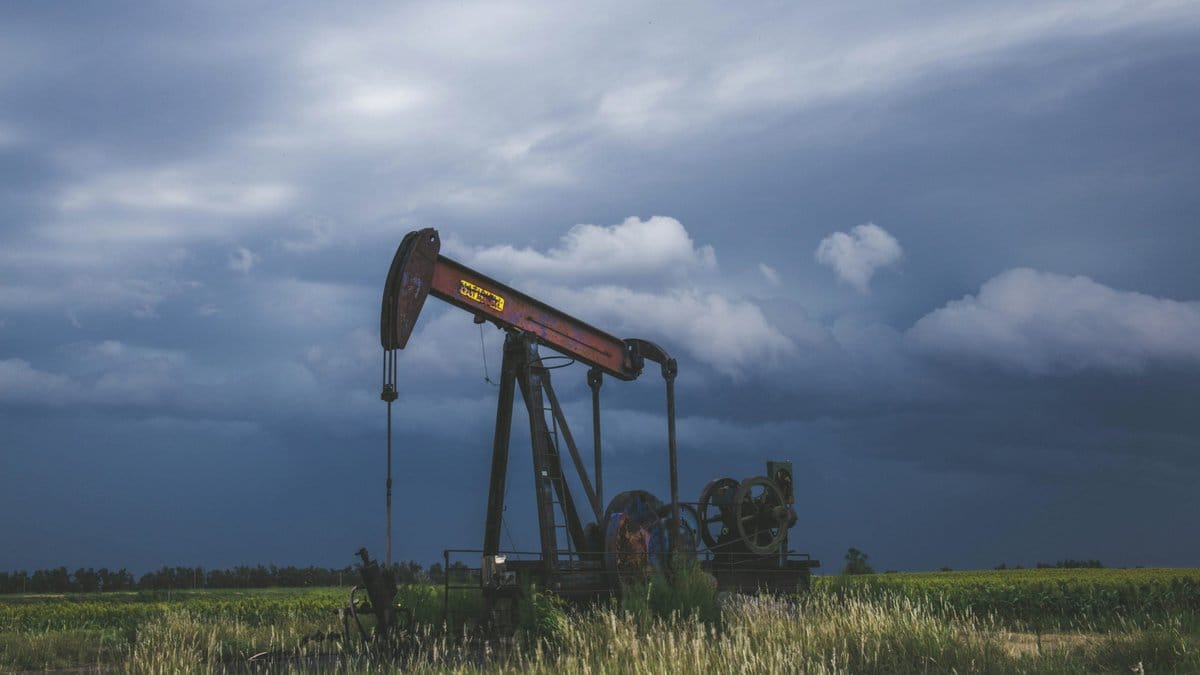 Pumpjack operating in a rural oil field beneath a cloudy sky