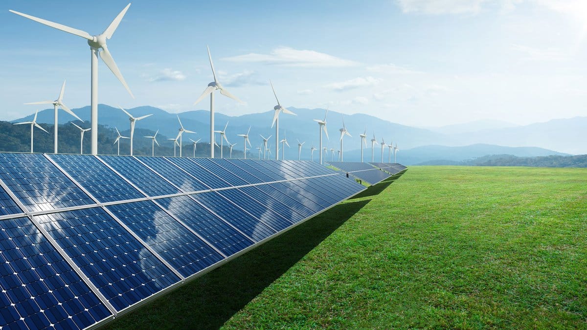 Solar panels and wind turbines in a green field, symbolizing the growth of renewable energy and the clean energy transition