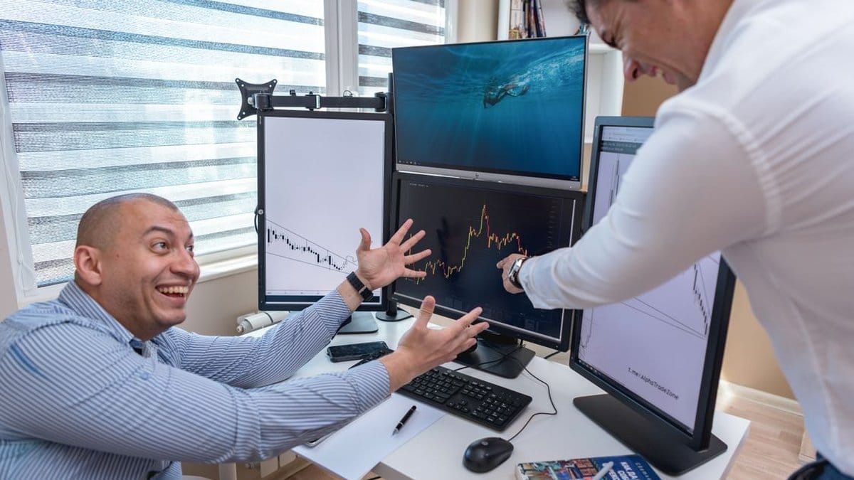 Financial analysts enthusiastically reviewing stock market charts on multiple trading monitors