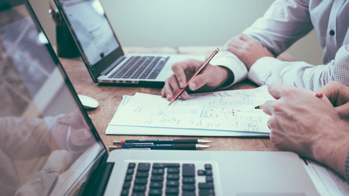 Financial analysts reviewing market data and economic reports — Fed Watch and economic outlook August 2026