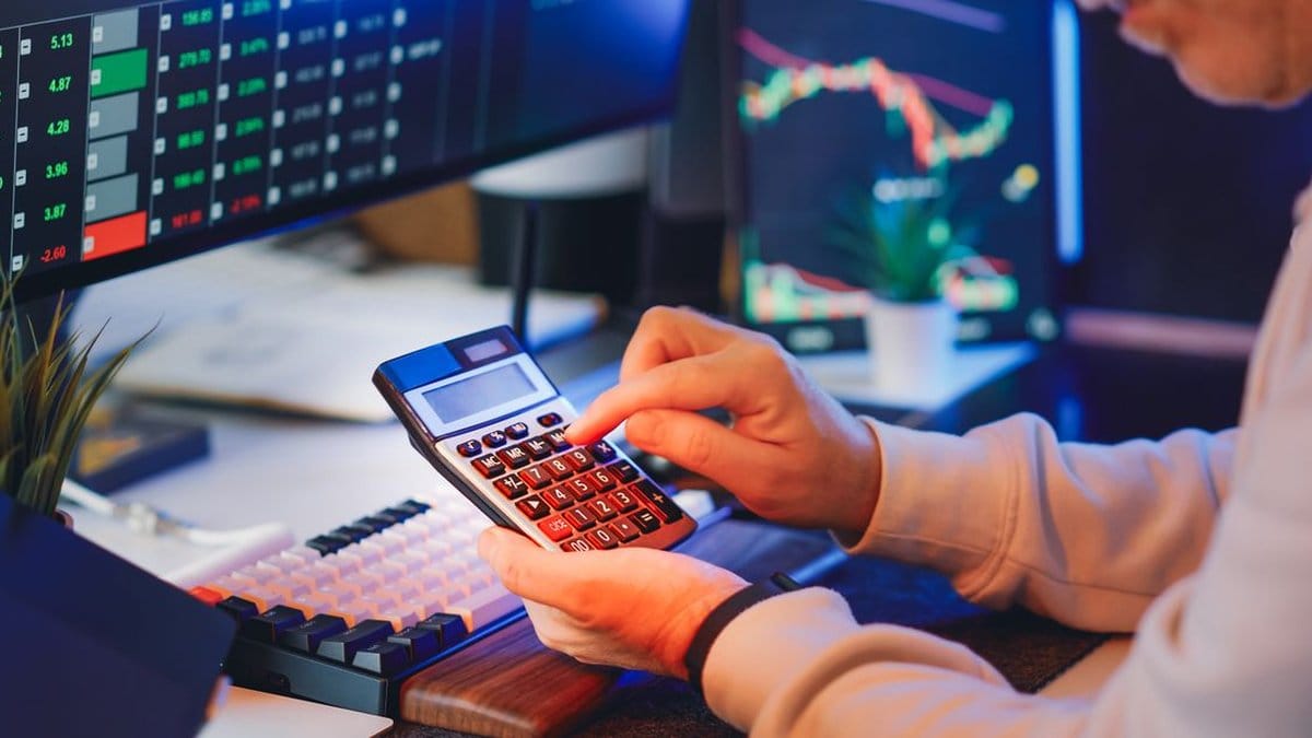 Financial professional reviewing market data and calculations at a trading desk