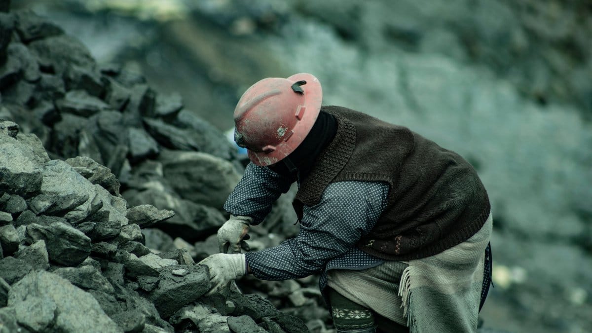 Mine worker examining mineral rock at an industrial mining site