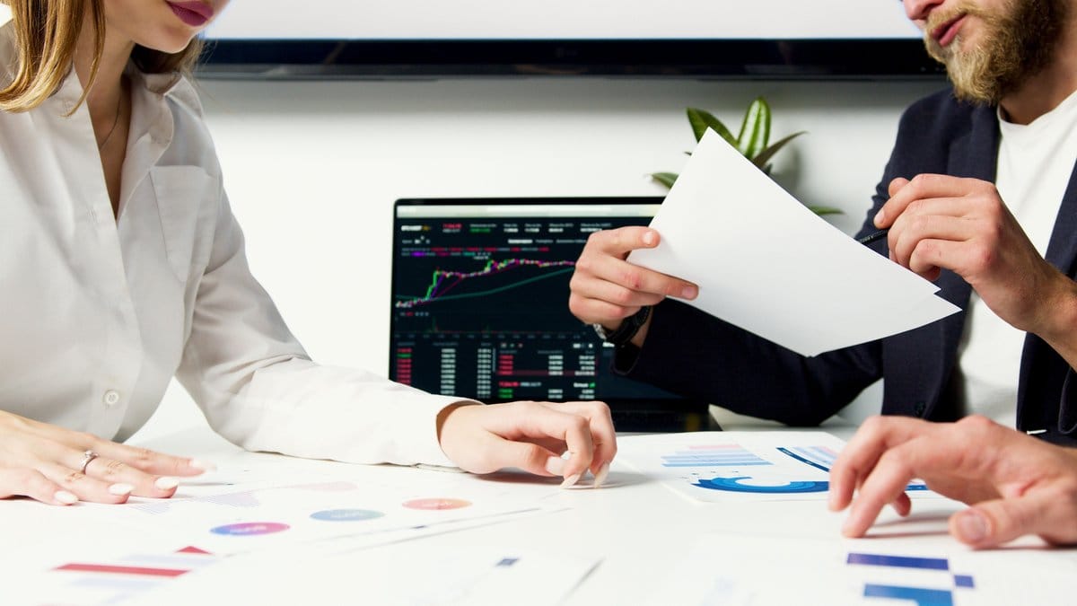 Financial analysts reviewing market charts and investment research at an office table