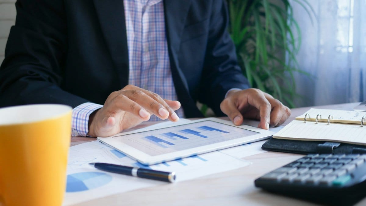 Financial analyst reviewing market performance data on a tablet and desk