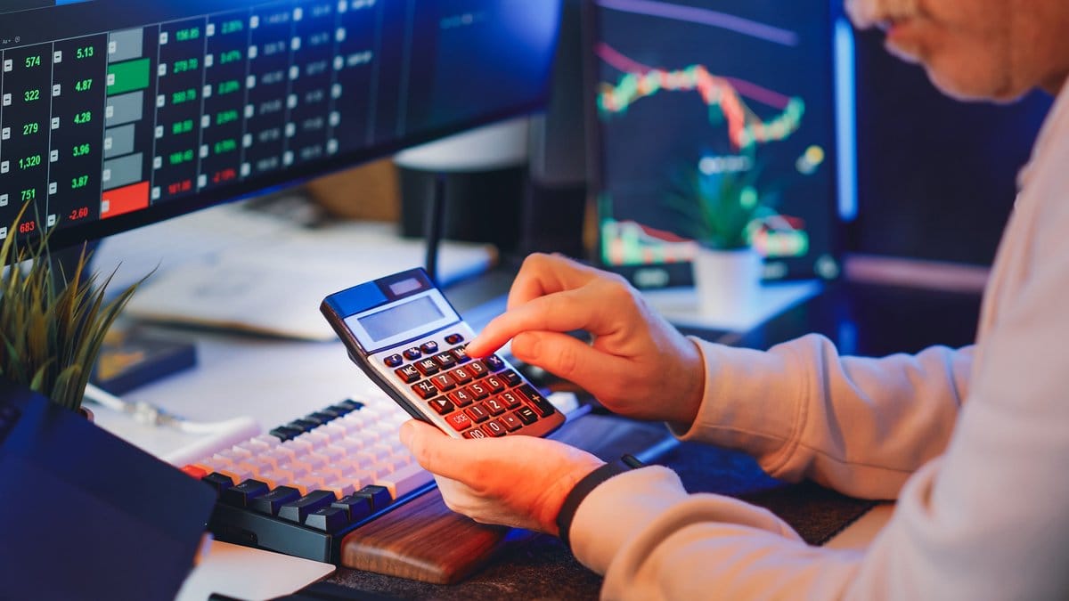 Financial analyst reviewing market data with calculator and trading screens