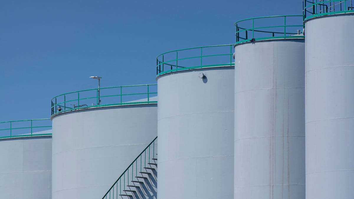 Industrial petroleum storage tanks at an energy facility under a clear blue sky