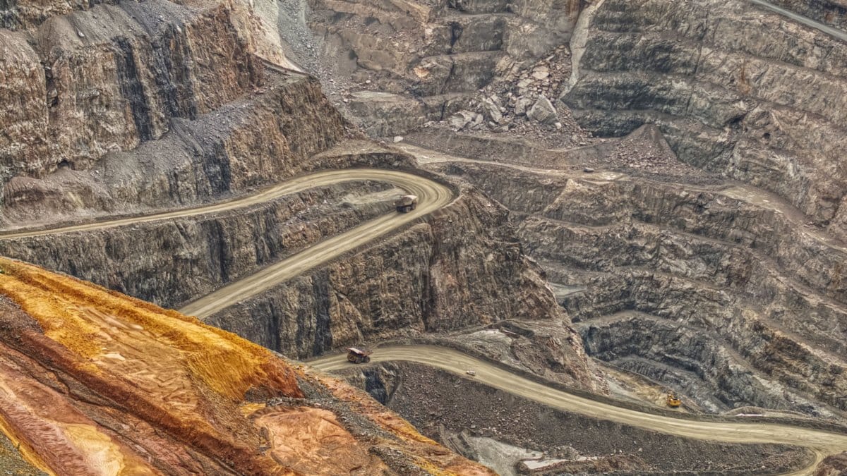 Open-pit mining operation with haul trucks illustrating precious metals supply