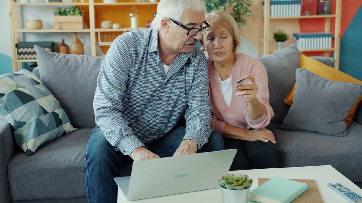 Retired couple using a laptop and financial documents to review retirement income choices