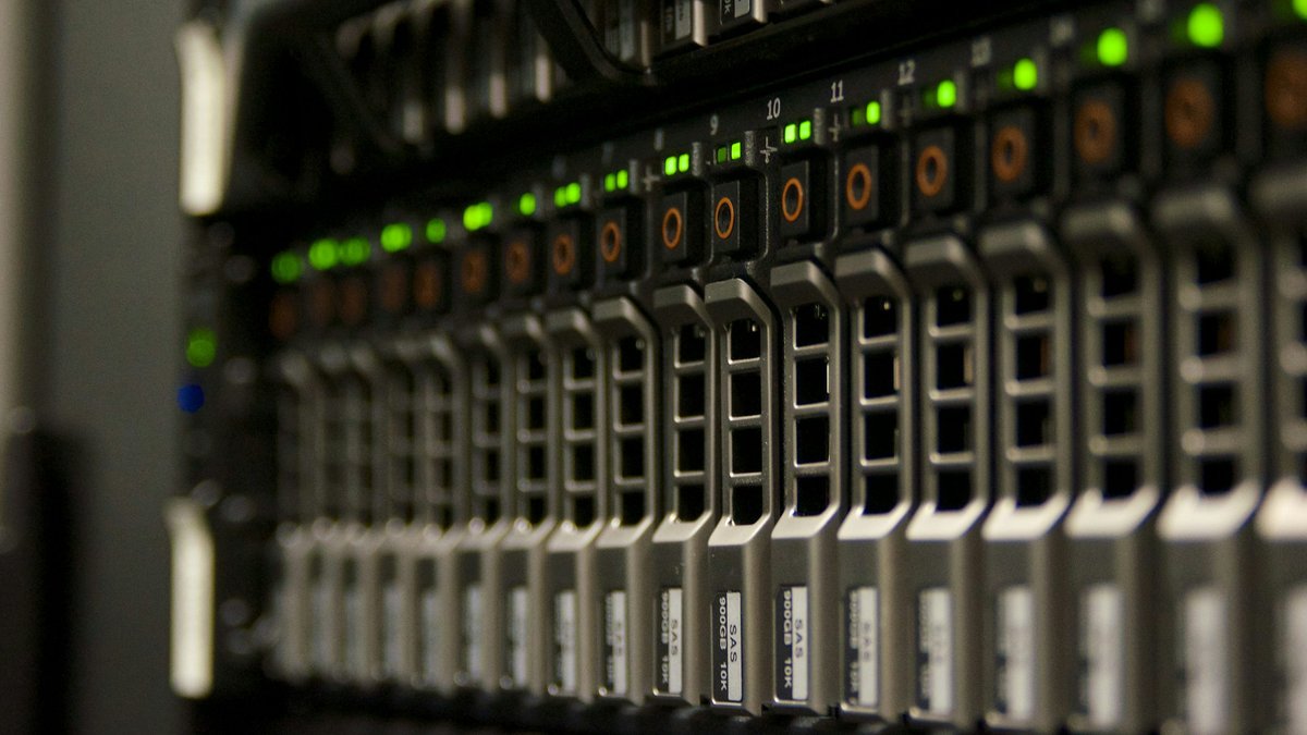 Data center server hardware with green indicator lights illustrating AI infrastructure spending and technology earnings