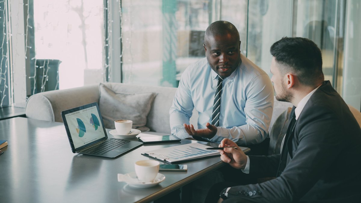 Business professionals reviewing financial documents and laptop charts during an office meeting