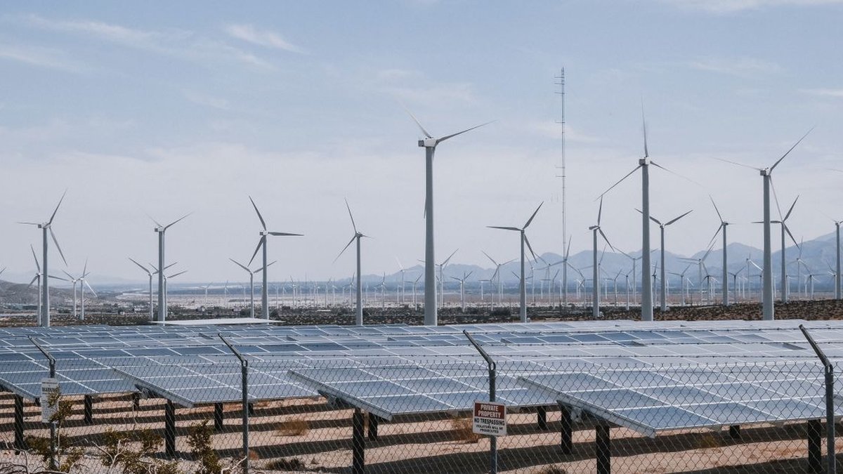 Solar panels and wind turbines at a renewable-energy farm under natural daylight
