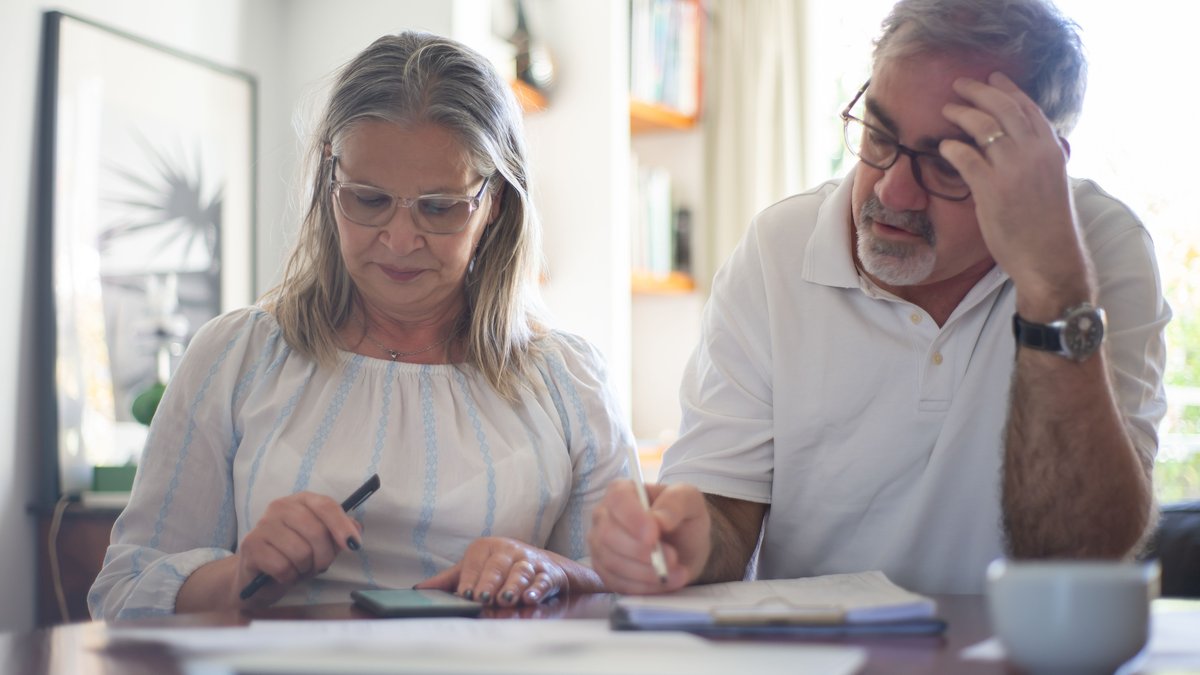 Senior couple calculating expenses and making notes for retirement withdrawal planning
