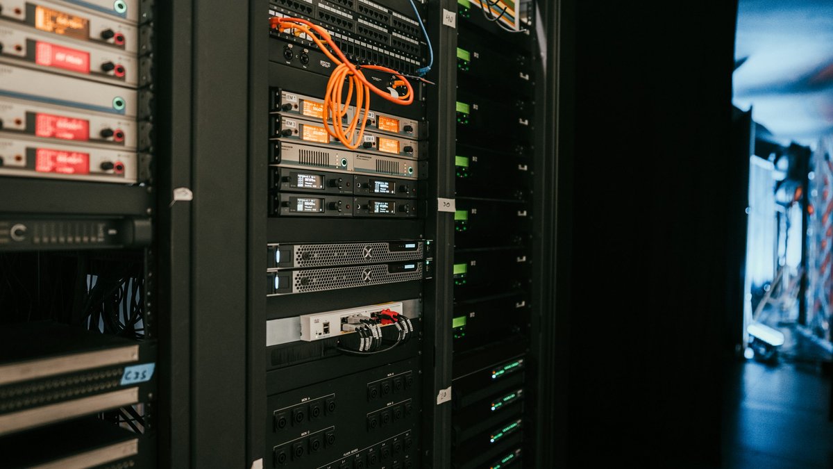 Close view of network and server racks with orange patch cables in a server room.